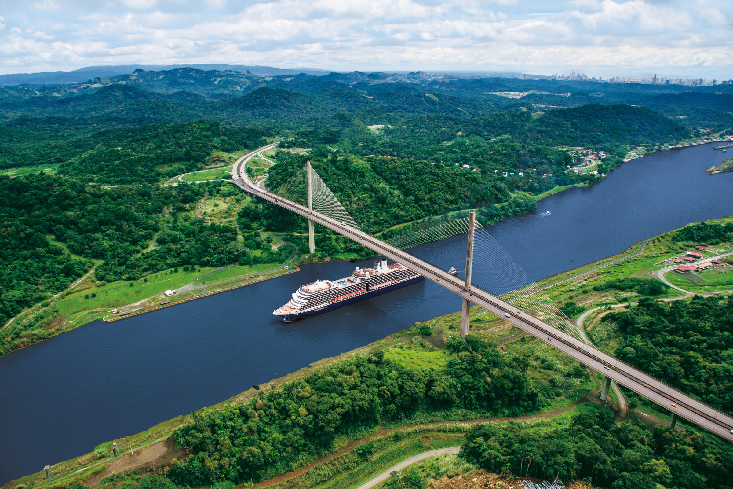 Cruise ship passes under a bridge while navigating through the Panama Canal.